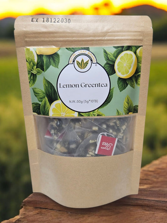 A standing pouch of Nutri-Leaf Brand Lemon Green Tea with a clear window showing tea leaves inside. The packaging is predominantly green with images of lemons and text detailing the product name and additional information.