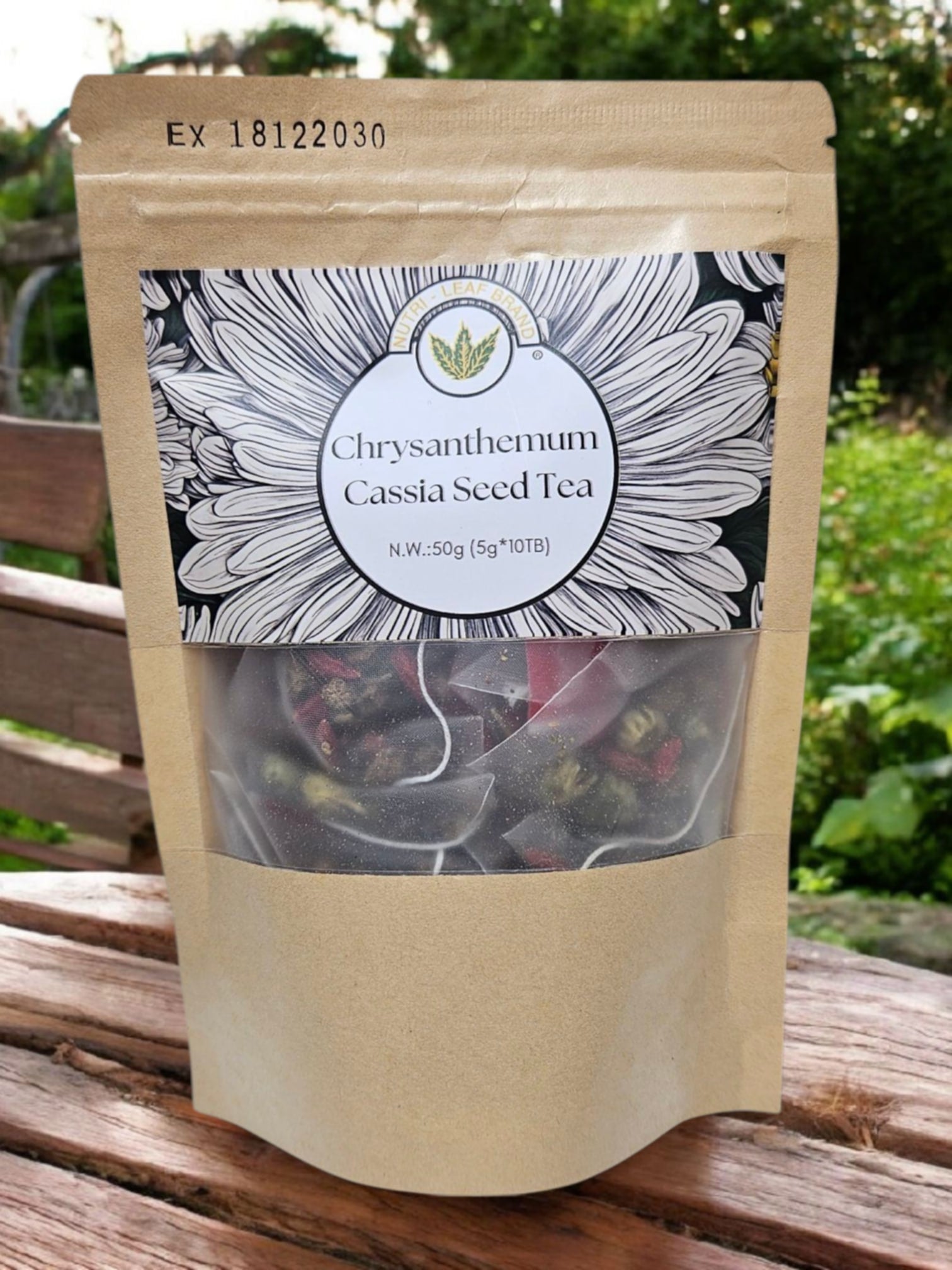 A pack of Nutri-Leaf Brand Chrysanthemum Cassia Seed Tea with a clear window showing the dried tea leaves inside. The packaging is primarily brown with a decorative white label on the front.