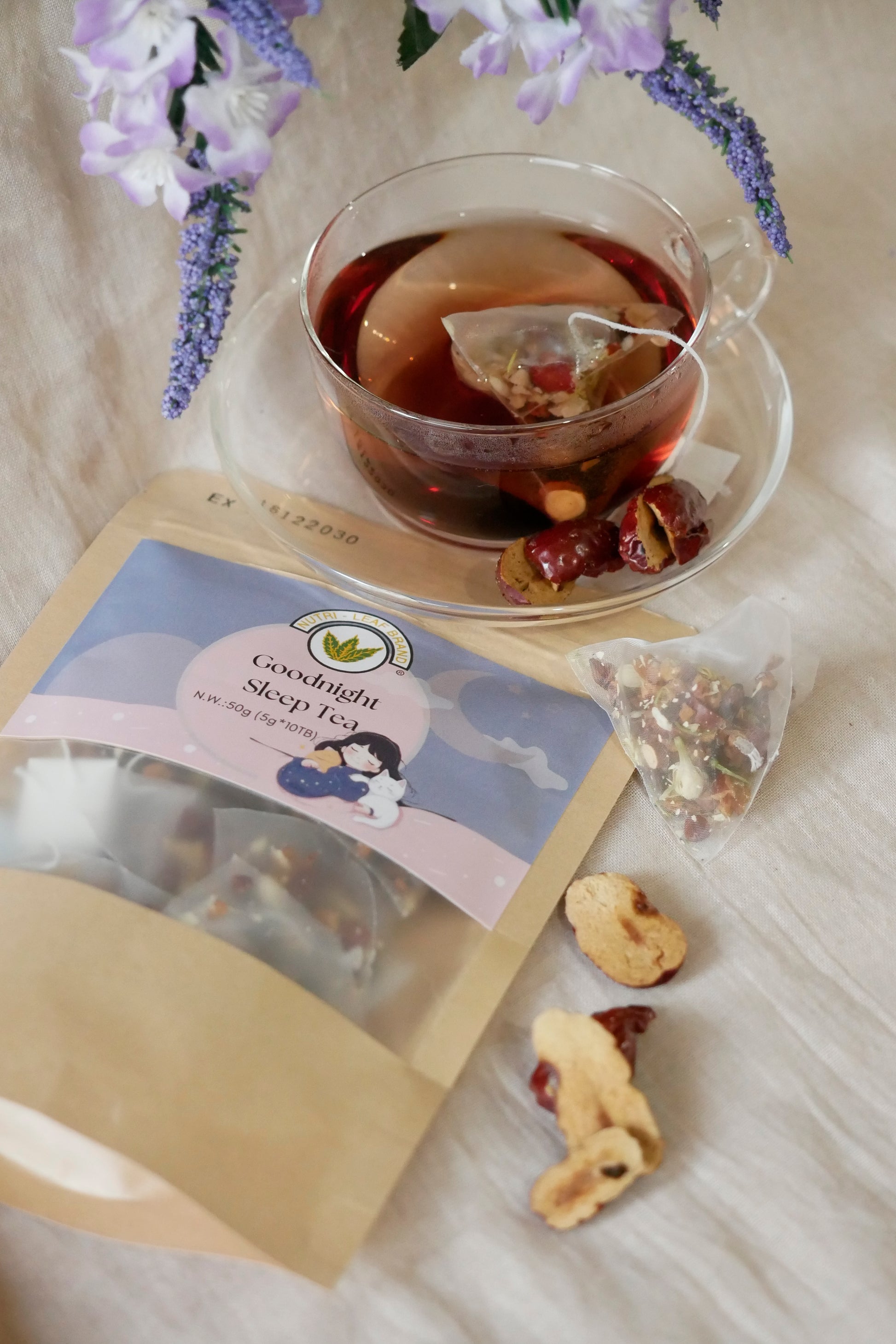 Tea bag with a label, a cup of tea, and dried fruits on a light surface with flowers.