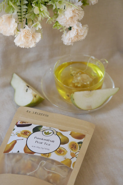 Glass tea cup with pear slices on the side and flowers on a light surface